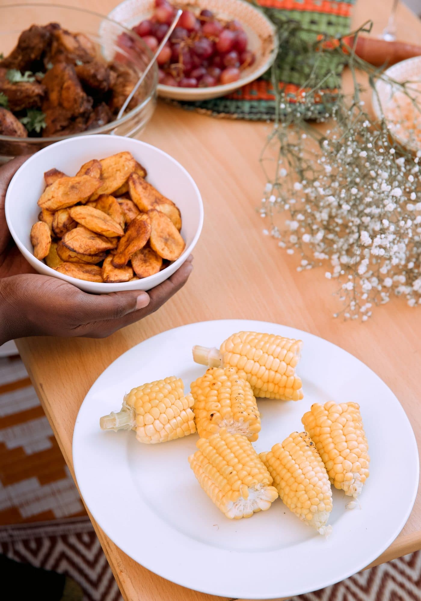 Un bol de plantains frits tenu à deux mains, au-dessus d'une table garnie